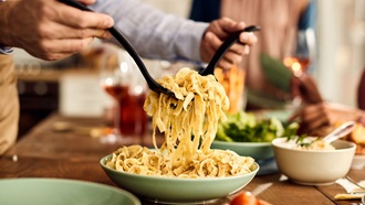 Homme qui mange des spaghettis à la sauce tomate